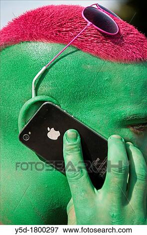 contemporary lifestyle of young people, man's face painted in green colour, hair painted in red, man talking by mobile phone, taken during Lake Parade in Geneva, Switzerland View Large Photo Image Stock Photo - contemporary lifestyle of young people, man's face painted in green colour, hair painted in red, man talking by mobile phone, taken during Lake Parade in Geneva, Switzerland. Fotosearch