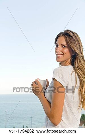 Content blonde woman having a drink in a balcony by the sea View Large Photo Image Stock Image - Content blonde woman having a drink in a balcony by the sea. Fotosearch