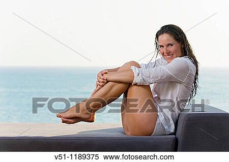 Stock Photography - Content brunette woman relaxing in the balcony by the sea. Fotosearch