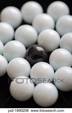 Contrasting white and black marbles used in game, one black pebble is left alone in opposition to all the white View Large Photo Image Stock Photograph - Contrasting white and black marbles used in game, one black pebble is left alone in opposition to all the white. Fotosearch