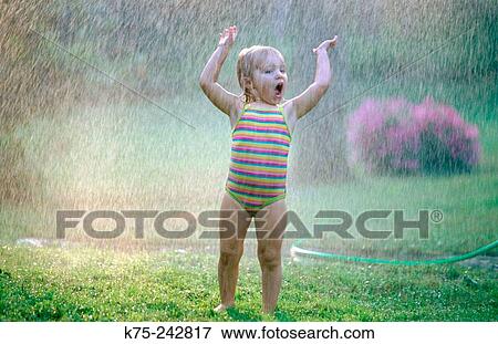 Cooling off in the sprinkler View Large Photo Image Stock Photo - Cooling off in the sprinkler. Fotosearch