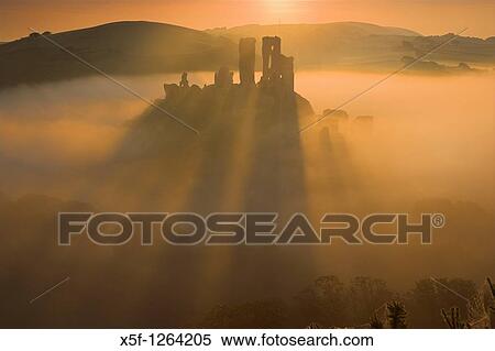 Corfe Castle back lit by the sun causing long shadows to appear as it rises out of the mist at dawn Purbeck Dorset View Large Photo Image Stock Photography - Corfe Castle back lit by the sun causing long shadows to appear as it rises out of the mist at dawn Purbeck Dorset. Fotosearch