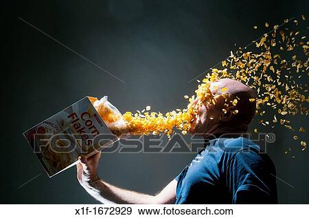 Corn flakes from a box cascading onto a man's face, conceptual image for overconsumption greed glutony View Large Photo Image Stock Photo - Corn flakes from a box cascading onto a man's face, conceptual image for overconsumption greed glutony. Fotosearch