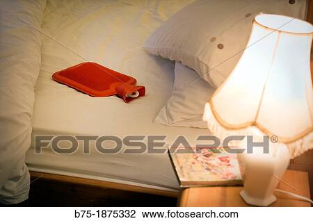 cossy atmosphere bedroom with bed, Bedside table, hot water bottle, book and lamp View Large Photo Image Stock Image - cossy atmosphere bedroom with bed, Bedside table, hot water bottle, book and lamp. Fotosearch