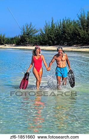 Stock Image - Couple 30s having fun at beach on vacation in Caribbean Mexico running in blue water with dive gear. Fotosearch