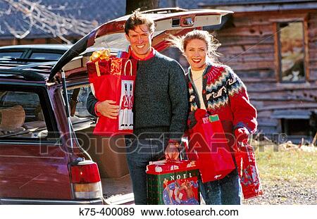 Couple at car with Christmas presents View Large Photo Image Stock Photo - Couple at car with Christmas presents. Fotosearch