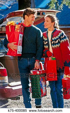 Stock Photography - Couple at car with Christmas presents. Fotosearch