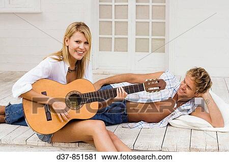 Couple at home playing guitar View Large Photo Image Stock Image - Couple at home playing guitar. Fotosearch