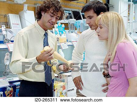 Stock Image - Couple buying a hand blender at shopping center. Fotosearch