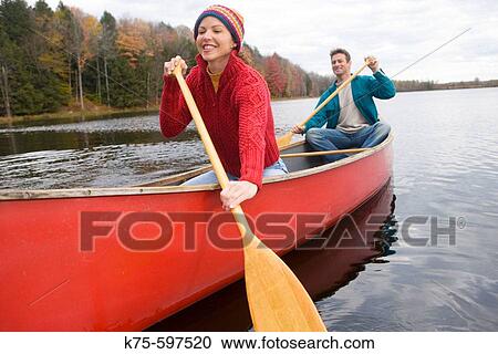 Stock Image - Couple canoeing on lake in autumn. Fotosearch