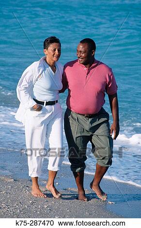 couple casually strolling down the beach View Large Photo Image Stock Image - couple casually strolling down the beach. Fotosearch