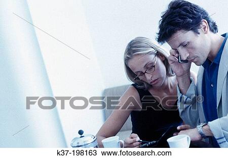 Couple checking time & info over coffee View Large Photo Image Stock Image - Couple checking time & info over coffee. Fotosearch