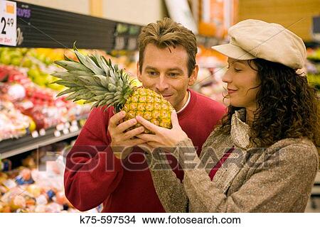 Picture - Couple choosing pineapple. Fotosearch
