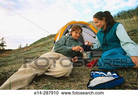 Stock Image - Couple cooking meal by tent. Chugach State Park. Southcentral Alaska. Fotosearch