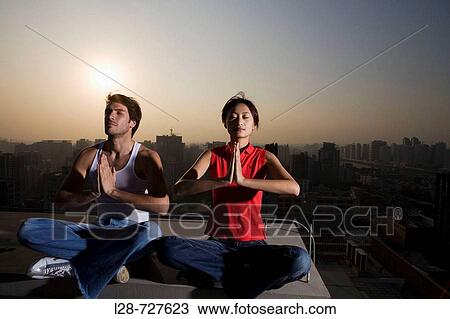 Couple doing Yoga with urban background View Large Photo Image Stock Image - Couple doing Yoga with urban background. Fotosearch