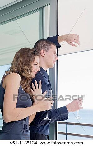 Couple drinking champagne looking at the sea at home View Large Photo Image Picture - Couple drinking champagne looking at the sea at home. Fotosearch