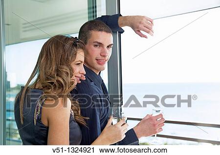 Couple drinking champagne looking at the sea at home View Large Photo Image Stock Image - Couple drinking champagne looking at the sea at home. Fotosearch