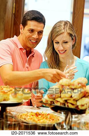 Stock Photograph - Couple drinking wine and eating tapas. Pintxos. Bar txondorra. Parte Vieja. Old town. San Sebastian. Donostia. Gipuzkoa. Basque Country. Spain.. Fotosearch
