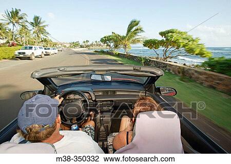 Stock Image - Couple driving in a convertible in Kauai. USA. Fotosearch