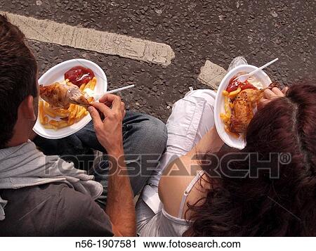 Stock Image - couple eating in the street, Notting Hill Carnival, London. Fotosearch