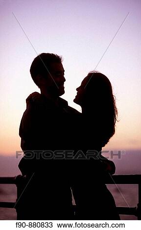 Couple embrace on pier at dusk View Large Photo Image Stock Image - Couple embrace on pier at dusk. Fotosearch