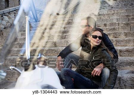Couple embrace on steps next to motor scooter, looking through the visor View Large Photo Image Stock Image - Couple embrace on steps next to motor scooter, looking through the visor. Fotosearch