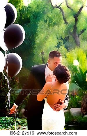 couple embracing, holding balloons in a garden setting View Large Photo Image Stock Photograph - couple embracing, holding balloons in a garden setting. Fotosearch