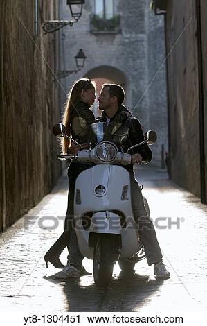 Stock Image - Couple embracing on a motor scooter. Fotosearch