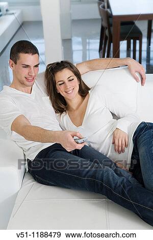 Stock Photo - Couple enjoying leisure at home watching TV. Fotosearch