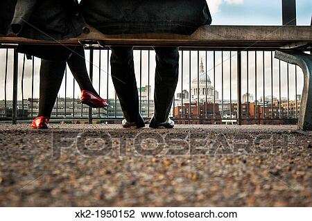 Stock Image - Couple flirting seated in a bench in front of St Paul's Cathedral, near Tate modern, London, UK. Fotosearch