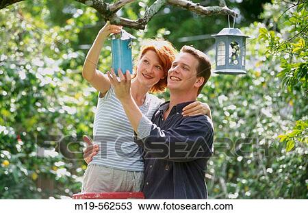 Stock Image - couple hanging a bird house. Fotosearch