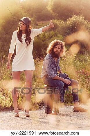 Stock Image - Couple hitch hiking on the side of the road. Tarifa, Cadiz, Andalusia, Spain, Europe.. Fotosearch