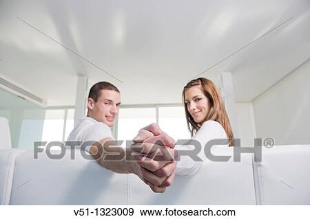 Couple holding hands in sofa View Large Photo Image Stock Photo - Couple holding hands in sofa. Fotosearch