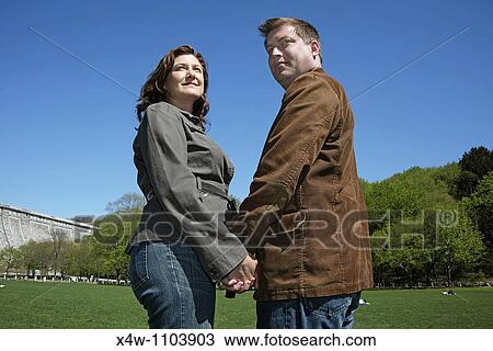 Couple holding hands on a sunny day in a park View Large Photo Image Stock Image - Couple holding hands on a sunny day in a park. Fotosearch