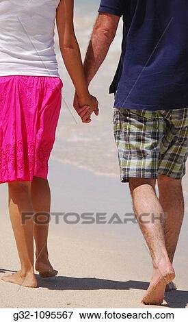 Stock Photo - Couple holding hands, walking on beach. Fotosearch