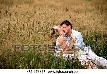 Couple hugging in a field View Large Photo Image Stock Photo - Couple hugging in a field. Fotosearch