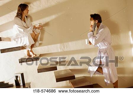 couple in bathrobe talking and drinking on stairs View Large Photo Image Stock Photograph - couple in bathrobe talking and drinking on stairs. Fotosearch