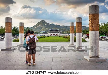 Couple in Gwanghwamun Square and ornamentation that accompanies the statue of King Sae Jong Dae in Gwanghwamun Square, in background Gyeongbokgung palace, Seoul, South Korea. View Large Photo Image Stock Photo - Couple in Gwanghwamun Square and ornamentation that accompanies the statue of King Sae Jong Dae in Gwanghwamun Square, in background Gyeongbokgung palace, Seoul, South Korea.. Fotosearch
