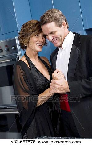 Stock Photo - Couple in kitchen getting ready for a formal night out.. Fotosearch