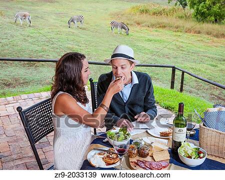 Couple in late twenties eating picnic lunch with zebras in background, on honeymoon in the Winelands, Western Cape, Stellenbosch, South Africa. View Large Photo Image Stock Photo - Couple in late twenties eating picnic lunch with zebras in background, on honeymoon in the Winelands, Western Cape, Stellenbosch, South Africa.. Fotosearch