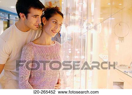 Stock Image - Couple in shopping center, looking at jewelry. Fotosearch