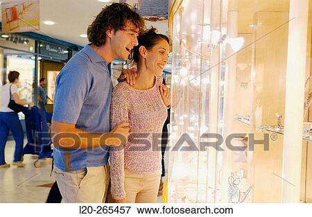 Stock Photo - Couple in shopping center, looking at jewelry. Fotosearch