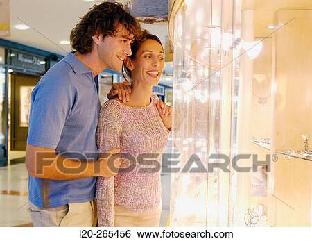 Stock Photograph - Couple in shopping center, looking at jewelry. Fotosearch