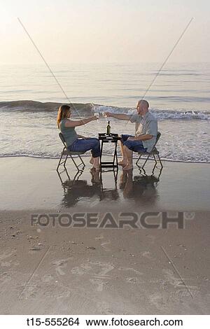 Couple in their 20's having a toast on the beach of ocean city, enjoying the sunset/sunrise View Large Photo Image Picture - Couple in their 20's having a toast on the beach of ocean city, enjoying the sunset/sunrise. Fotosearch