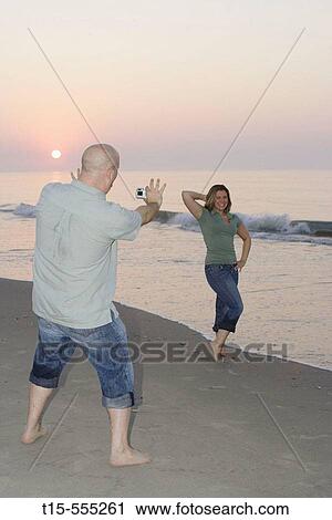 Couple in their 20's having fun on the beach of ocean city taking pictures during sunrise/sunset View Large Photo Image Stock Image - Couple in their 20's having fun on the beach of ocean city taking pictures during sunrise/sunset. Fotosearch