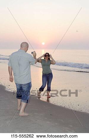 Couple in their 20's having fun on the beach of ocean city taking pictures during sunrise/sunset, she plays with donuts as glasses View Large Photo Image Stock Image - Couple in their 20's having fun on the beach of ocean city taking pictures during sunrise/sunset, she plays with donuts as glasses. Fotosearch