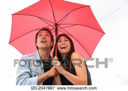 Stock Photo - Couple in their 30's smiling under umbrella.. Fotosearch