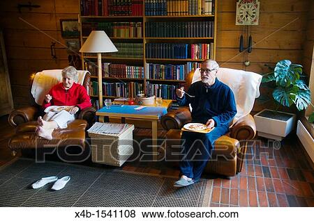 Couple in their early 70s eating and watching television Finland Europe View Large Photo Image Stock Photo - Couple in their early 70s eating and watching television Finland Europe. Fotosearch