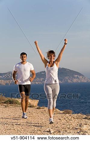 Couple jogging in a cliff by the sea in Ibiza View Large Photo Image Picture - Couple jogging in a cliff by the sea in Ibiza. Fotosearch