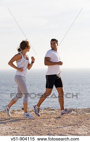 Stock Photography - Couple jogging in a cliff by the sea in Ibiza. Fotosearch